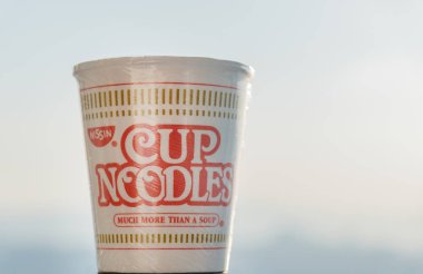 Vladivostok, Rusya - 16 Kasım 2017: Nissin fincan şehriye gökyüzü arka plan üzerinde. Seçici odak. Anlık erişte Momofuku Ando tarafından 1958 yılında icat edildi.