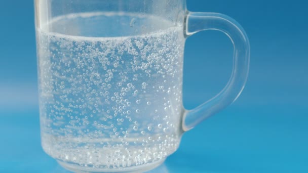 Bubblande Piller Ett Glas Vatten Blå Bakgrund — Stockvideo