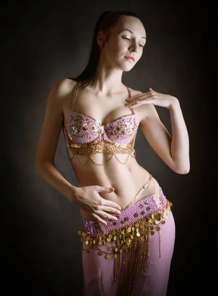 Exotic belly dancer woman with perfect body on a dark background.