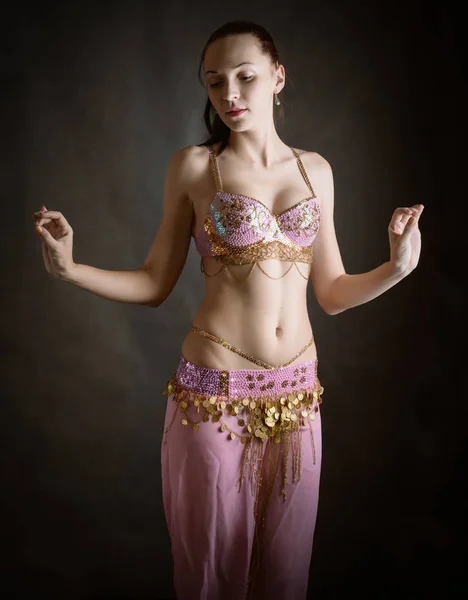 Exotic belly dancer woman with perfect body on a dark background.