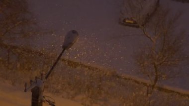 Geceleri şehirdeki sokak lambası arka plan üzerine düşen kar.