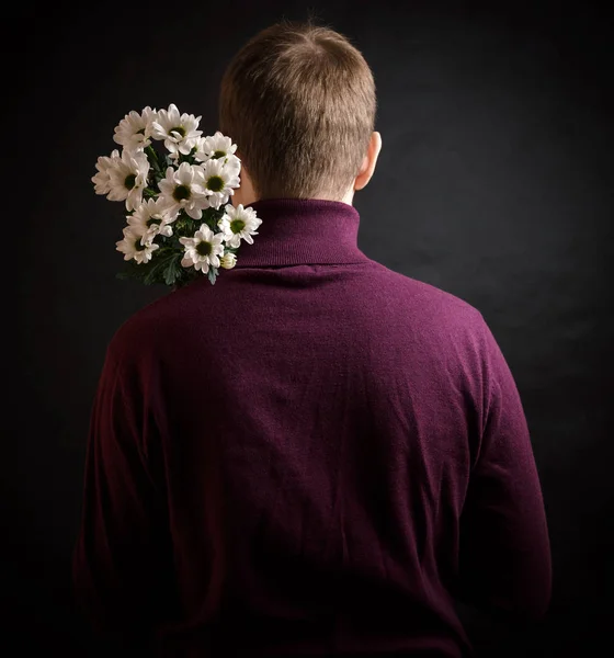 若い男が彼の背中の後ろに花を非表示 — ストック写真