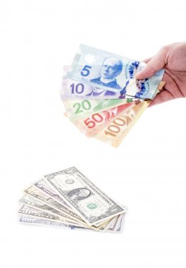 Handful of Canadian Dollar Bills Verses a Pile of US Dollar Bills clipart