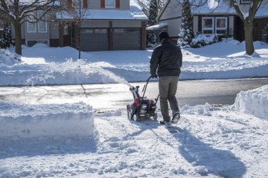 Güneşli bir günde bir kar temizleme makinesi ile kar kaldırma adam