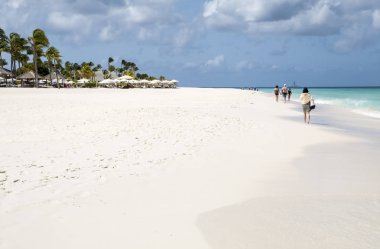 Eagle Beach, Aruba - 10 Nisan 2018: Güzel kartal sahil boyunca yürüyüş insanlar bu sonsuza kadar gidiyor... Uzaktan bir Offshore sondaj istasyonu var