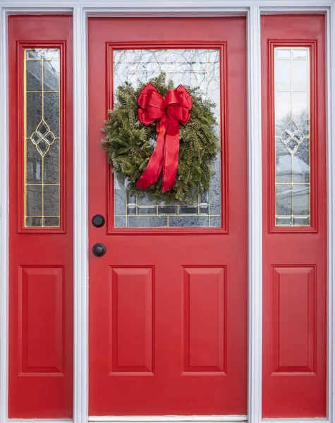 红房子门装饰有一个真正的松树圣诞花环和一个大红色缎子弓 — 图库照片