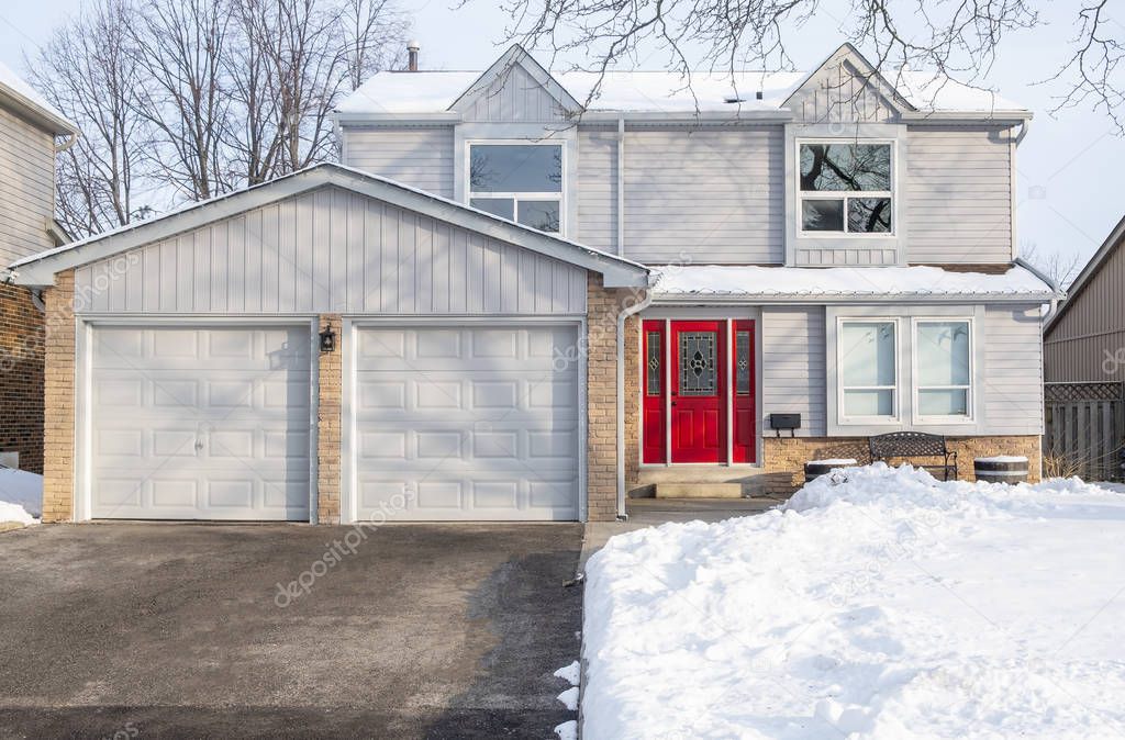 Typical Suburban Detached House with Grey Siding and Red Door After Snow