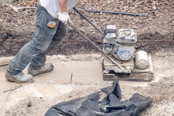 Arbeiter Betätigt Einen Plattenverdichter Auf Schlammigem Boden — Stockfoto