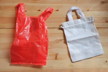 Plastik torba ve tahta zemindeki beyaz bez çanta, plastik poşetleri çevre dostu ürünlerle değiştirmek ve atık, sıfır atık, küresel ısınma kavramını azaltmak için.