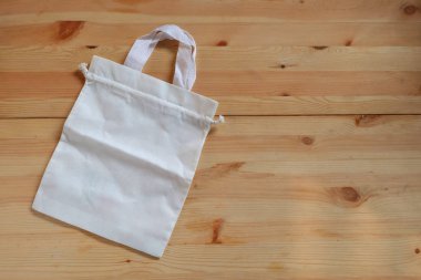 Ahşap zemine boş beyaz bez torba, plastik poşetleri çevre dostu ürünlerle değiştirmek ve atıkları azaltmak, sıfır atık, küresel ısınma kavramı.