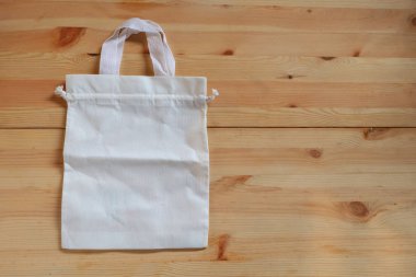 Ahşap zemine boş beyaz bez torba, plastik poşetleri çevre dostu ürünlerle değiştirmek ve atıkları azaltmak, sıfır atık, küresel ısınma kavramı.