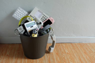 Elektronik atık, beyaz duvarlı geri dönüşüm kutusunda kırılmış veya hasar görmüş ve metin girdisi, yeniden kullanım ve geri dönüşüm konsepti için yukarıda boşluk bırakılmış.