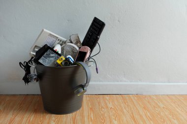 Elektronik atık, beyaz duvarlı geri dönüşüm kutusunda kırılmış veya hasar görmüş ve metin girdisi, yeniden kullanım ve geri dönüşüm konsepti için yukarıda boşluk bırakılmış.