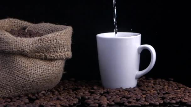 咖啡杯和咖啡豆 把水倒入杯子里 旧袋子上的咖啡豆 — 图库视频影像