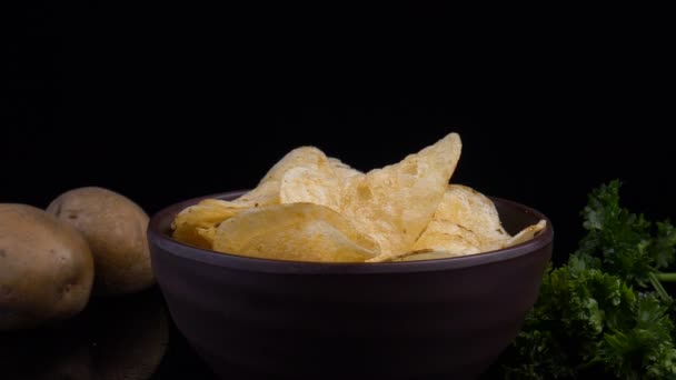 Kartoffelchips und rohe Kartoffeln auf schwarzem Hintergrund — Stockvideo