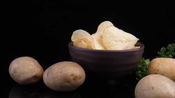 Potato chips and raw potato on black background — Stock Video