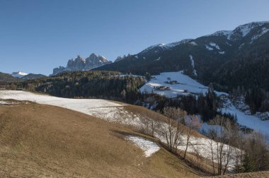 Kışın İtalya 'da Dolomitler. Alp çayırı kısmen karla kaplı orman ve kayaların arka planına karşı