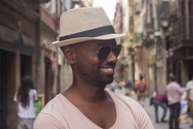 Eski bir şehir sokaklarında gülümseyen bir beyaz şapka ve havacı güneş gözlüğü ile adam genç Hintli siyah sakallı