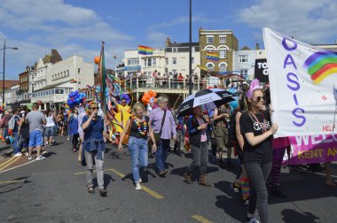  İnsanlar taşıma bayraklar ve renkli Gay Pride Parade, Margate, İngiltere'de yürüyen afiş.