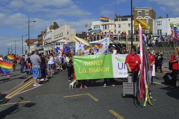 MARGATE, UK-AUGUST 12: Crowds watch people carrying flags and banners marching in the colourful Gay Pride Parade, part of the annual Margate Pride festival. August 12, 2017 in Margate, UK. — Stock Photo, Image