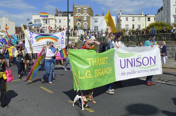 Crowds watch people carrying flags and banners marching in the colourful Gay Pride Parade, part of the annual Margate Pride festival. August 12, 2017 in Margate, UK. — Stock Photo, Image