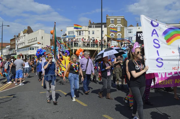  İnsanlar taşıma bayraklar ve renkli Gay Pride Parade, Margate, İngiltere'de yürüyen afiş.