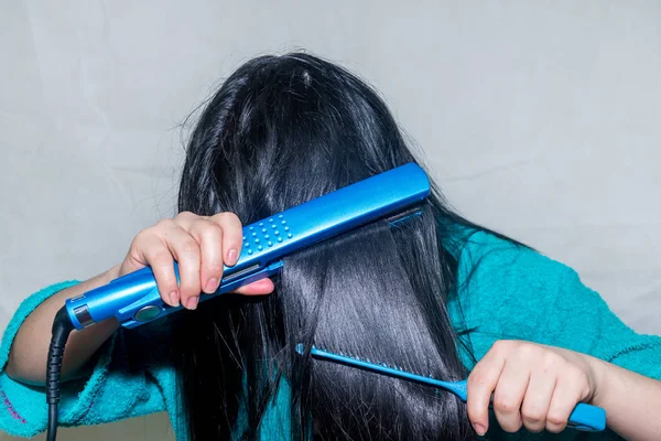 Mujer planchándose el pelo Fotos De Stock Sin Royalties Gratis