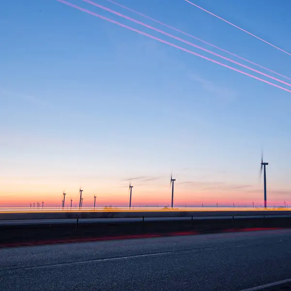 Wind turbines at sunset along highway morning commute — Stock Photo, Image