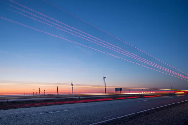 Windturbines bij zonsondergang langs snelweg ochtend pendelen — Stockfoto