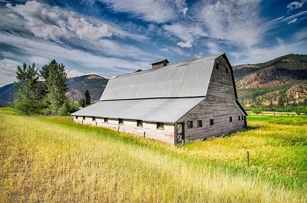 Atardecer de verano con un granero rojo en Montana rural y Rocky Mountai — Foto de Stock