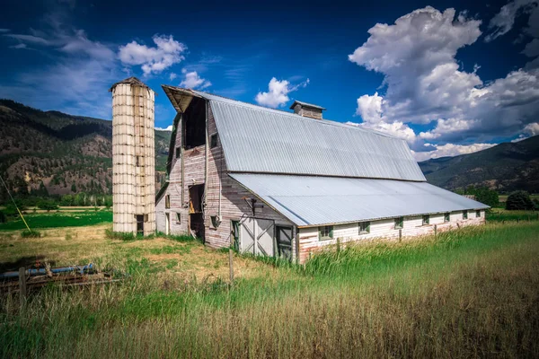 Atardecer de verano con un granero rojo en Montana rural y Rocky Mountai — Foto de Stock