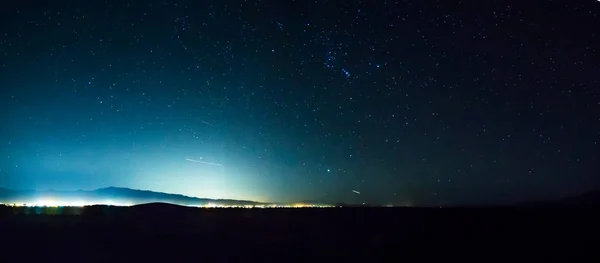 Céu noturno no vale da morte com luzes da cidade pahrump na distância — Fotografia de Stock