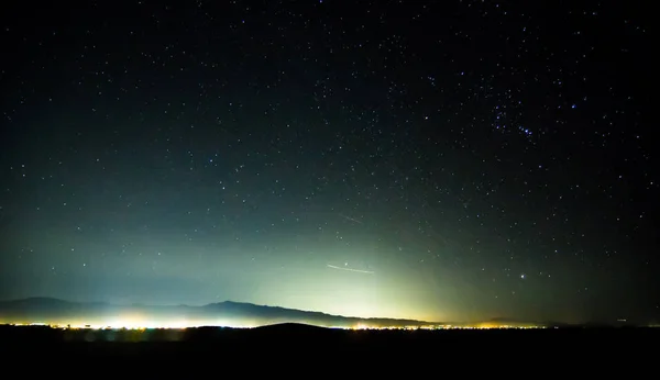 Céu noturno no vale da morte com luzes da cidade pahrump na distância — Fotografia de Stock