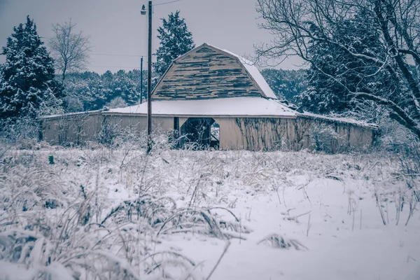 Свежий снег лежит на земле вокруг старого амбара — стоковое фото