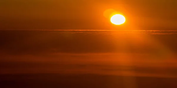 Pôr do sol ou nascer do sol de um avião espreitando pelas nuvens — Fotografia de Stock