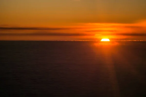 Zachód lub wschód słońca z samolotu, zerkające przez chmury — Zdjęcie stockowe