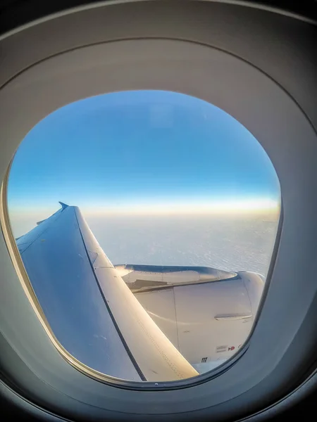 Olhando para a janela do avião e voando acima das nuvens — Fotografia de Stock