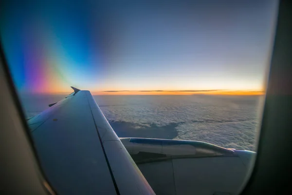 Nuvens e céu como visto através da janela de uma aeronave ao nascer do sol — Fotografia de Stock