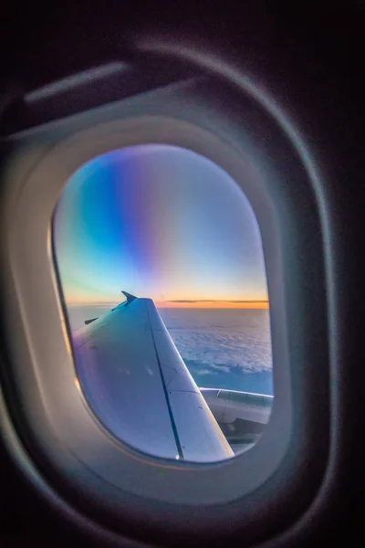Nuages et ciel vus à travers la fenêtre d'un avion au lever du soleil — Photo