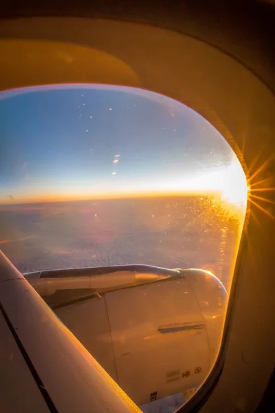 Nuages et ciel vus à travers la fenêtre d'un avion au lever du soleil — Photo