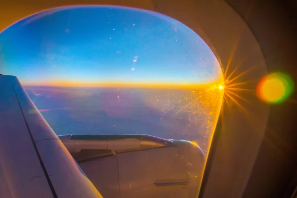 Nuages et ciel vus à travers la fenêtre d'un avion au lever du soleil — Photo