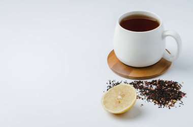 Bambu destekli beyaz bardakta meyve çayı, limon ve kurutulmuş te.