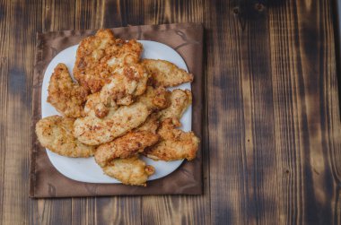 Tahta bir masada beyaz bir kasede kızarmış çıtır nugget. Üst görünüm