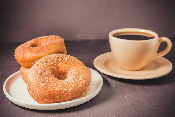 Donuts em uma chapa e uma xícara de café preto. Foco seletivo . — Fotografia de Stock