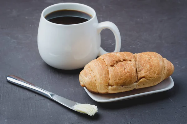 Desayuno francés. Taza blanca con café negro y cruasán con — Foto de Stock