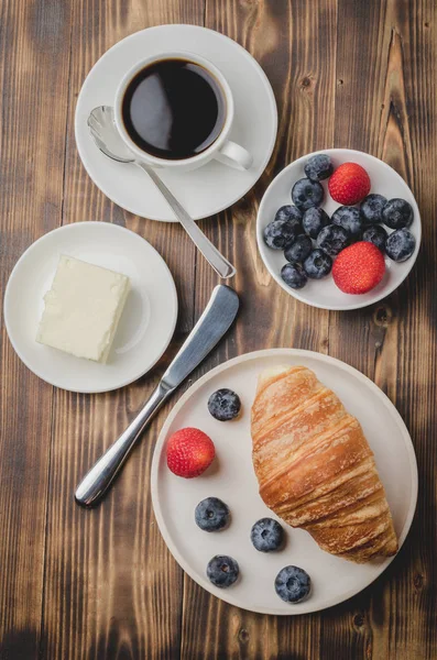 Taza de café, croissant con bayas en tazón blanco y cuchillo de mantequilla — Foto de Stock