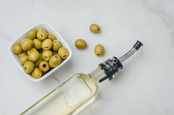 Botella de vidrio de aceite de oliva y oliva en un tazón blanco en un s blanco — Foto de Stock