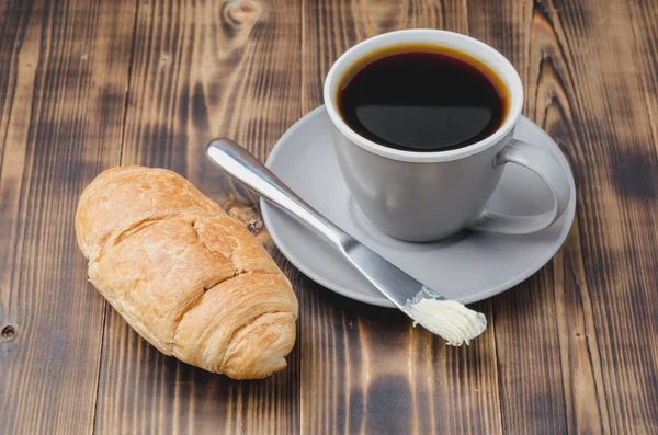 Pausa para café con cuchillo de mantequilla de croissant y taza de café negro — Foto de Stock