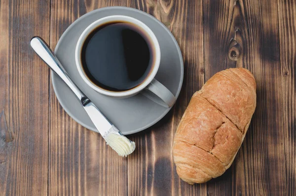 Kávészünet croissant vajkés és egy csésze fekete kávé — Stock Fotó