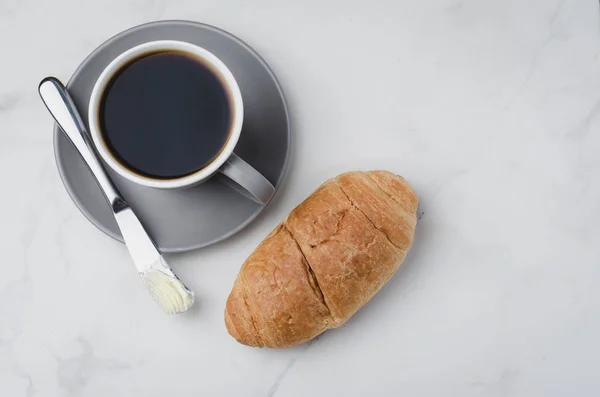 Pausa para café con cuchillo de mantequilla de croissant y taza de café negro — Foto de Stock